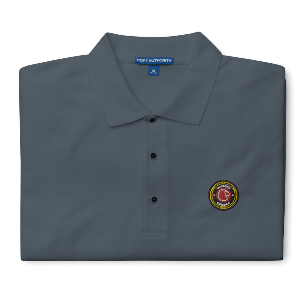 A premium embroidered polo featuring the Lion’s Den Member logo on the chest, available in six colors: Black, Red, Steel Grey, Cool Grey, Stone, and White. Classic design with soft cotton-poly fabric for ultimate comfort.